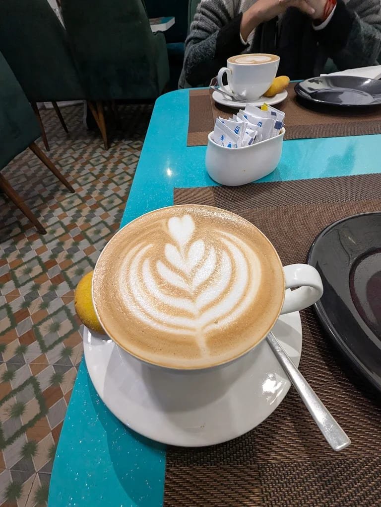 Rosetta latte art in a cup on a teal table